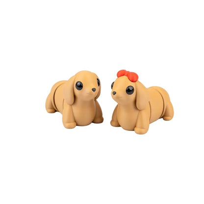 Two small dog figurines on a white surface with decorative flowers in the background.