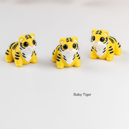 Three small tiger figurines on a white background